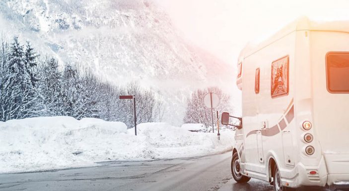 Camper sul lato della strada con paesaggio montano innevato sullo sfondo