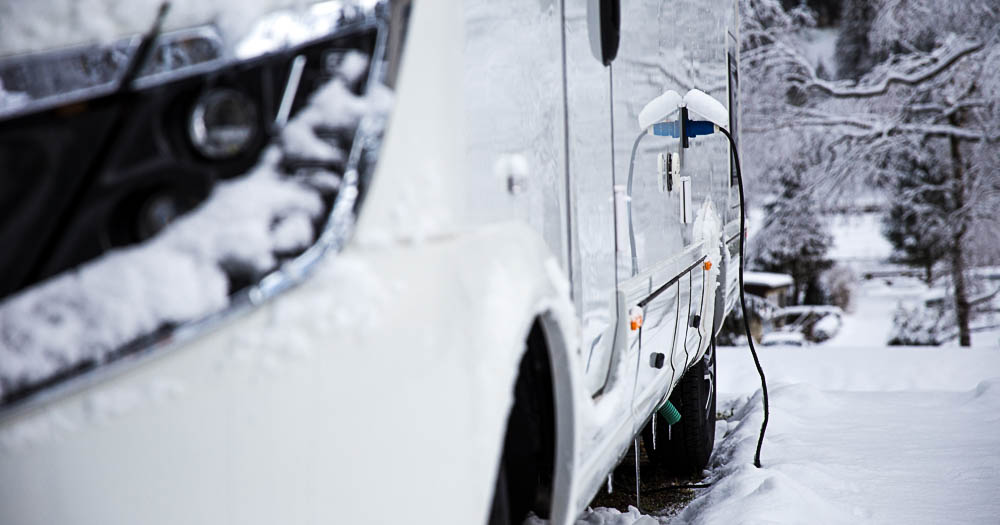 primo piano del cavo di connessione elettrica del camper a una presa in un campeggio innevato