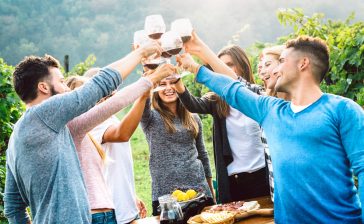 Friends raising a glass of wine at an Italian vineyard on a wine holiday in Italy