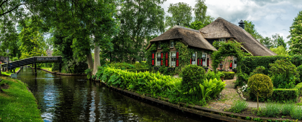 Overijssel canal site cottage with red shutters, Netherlands