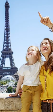 Mutter und Kind deuten auf etwas außerhalb des Bildes, im Hintergrund der Eiffelturm