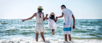 Famille heureuse jouant dans les vagues sur la plage en juin