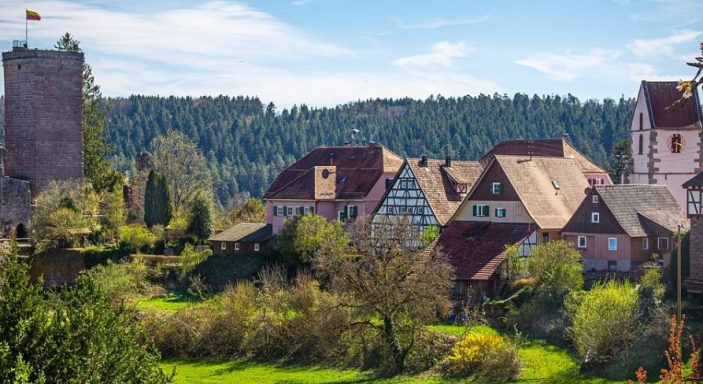 Grüne Landschaft im Schwarzwald, Deutschland mit Fachwerkhäusern und Burg im Hintergrund