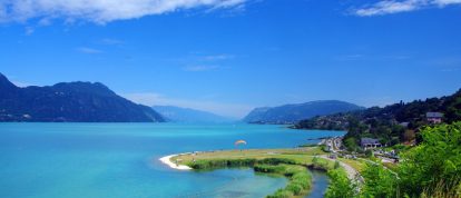 Vista sobre el lago Bourget con veraneantes disfrutando de la orilla del lago con un parapente - Campings en Aix-les-Bains